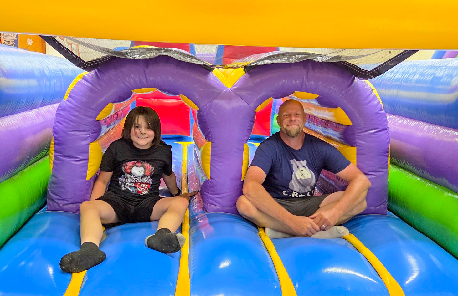 a CREST volunteer sits on a bouncey house with a student